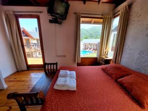 波特雷罗德洛斯弗内斯Cabañas Ayres del Lago 2的一间卧室配有红色的床和2条毛巾