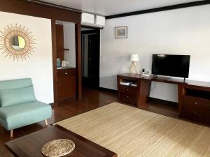 阿鲁埃Tahiti Lafayette Beach Lodge的客厅配有电视、椅子和桌子