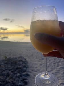 阿罗朗吉Rarotonga Villas Absolute Beachfront的手持一杯海滩上的葡萄酒