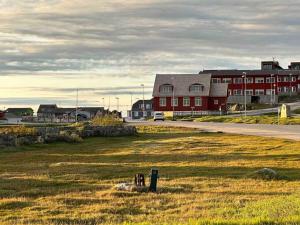 努克Nuuk Villa Hostel的一片草场,有一座红色的建筑和一条道路