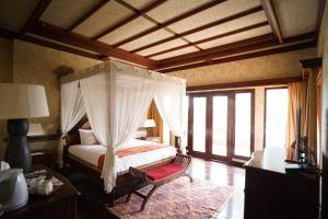 不拉士打宜Balinese Villa in Berastagi的一间带天蓬床的卧室,位于带窗户的房间内
