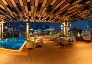 胡志明市Northern Charm Hotel的屋顶甲板设有游泳池和桌椅