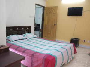 达卡Golpata Bed & Breakfast的卧室配有床、电视和门