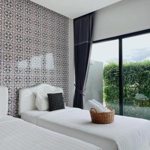 Tha Sala万纳察尔特精品度假酒店的一间卧室设有两张床和窗户。