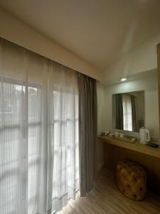 琅勃拉邦Midnight Blue Guesthouse的客房设有带窗帘和椅子的大窗户。