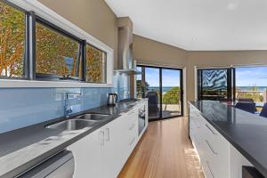 阿波罗湾阿基里斯度假屋 的厨房配有白色橱柜、水槽和窗户。