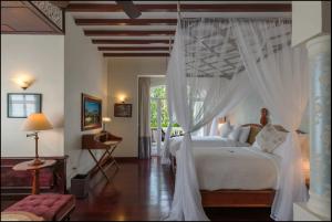 琅勃拉邦露塞公寓式酒店的一间卧室配有一张带天蓬的白色床