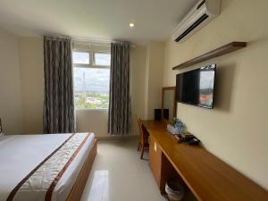 朔庄Quê Tôi 2 Hotel的酒店客房配有一张床、一张书桌和一台电视。