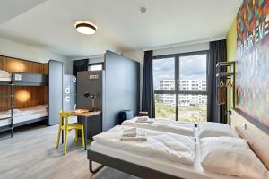 科隆MEININGER Hotel Köln West的一间卧室配有一张床、一张书桌和一个窗户。