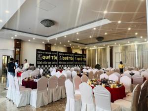 朔庄Quê Tôi 2 Hotel的宴会厅配有白色的桌椅和人手