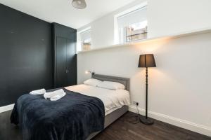 伦敦Stylish 2 bedroom at Hammersmith的一间卧室配有床、灯和窗户