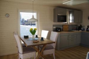 施特拉尔松德Hausboot Liliput的厨房配有木桌、椅子、桌子和窗户。