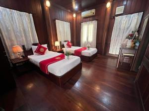 琅勃拉邦Villa Vieng Sa Vanh Hotel的客房内设有两张床,配有木地板和窗户。