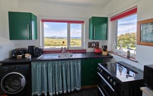 马林Teach Róisin-Traditional Irish holiday cottage in Malin Head.的厨房配有绿色橱柜、水槽和窗户
