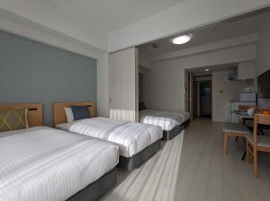 大阪ESLEAD HOTEL Namba Daikokucho的酒店客房设有三张床和一张桌子