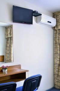 蒙得维的亚希斯潘诺酒店的一间设有两把椅子和一台墙上的电视的房间