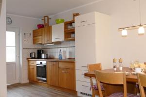 维特Hus-Hiddensee-Eckhaus-A的带餐桌的厨房和带白色橱柜的厨房