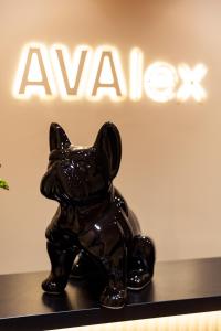 柏林Hotel AVAlex的坐在标牌前架上的狗雕像