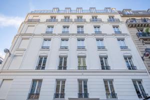 巴黎Résidence Le Belleville的一座高大的白色建筑,设有窗户和阳台