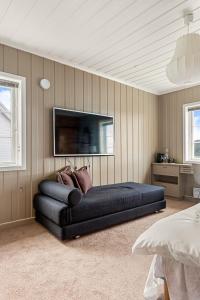 卑尔根Dinbnb Homes I Luxury Villa with Hot Tub & Views的墙上有电视的房间里一张黑色的沙发