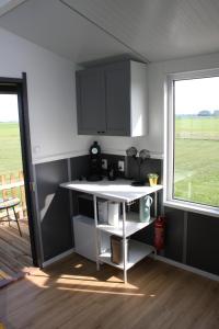 BurumBoerenchalet Dirk, Minicamping de Grutte Earen的厨房配有白色的柜台和窗户。