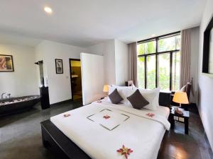 暹粒The Bliss Angkor的一间卧室配有一张白色大床,床上有鲜花