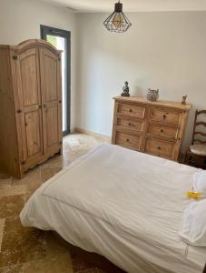 Plan dʼAupsChambre d hôtes LA MANDALA的一间卧室配有一张大床和一个木制梳妆台