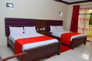 姆特瓦帕White Peacock Resort Mtwapa的一间卧室配有两张红色和白色床单