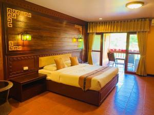 梅萨隆ดอยหมอกดอกไม้รีสอร์ท DoiMok DokMai Resort的一间卧室配有一张大床和木制床头板