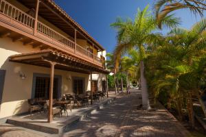 梅罗那瑞斯Lopesan Villa del Conde Resort & Thalasso的一座配有桌椅的建筑,棕榈树