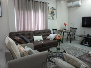 Himma's Apartments的客厅配有棕色皮沙发和桌子