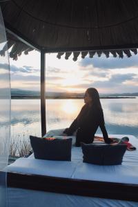 普诺Titicaca Ecolodge Perú的坐在水面上床边的女人