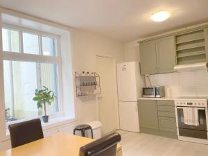 奥勒松Ålesund City Center - Modern 80-m2 flat with 3 bedrooms的厨房配有桌子、冰箱和窗户。