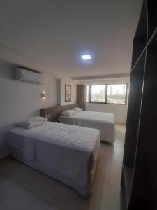 若昂佩索阿Manaíra Apart Hotel的酒店客房设有两张床和窗户。