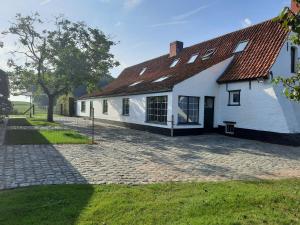 贝尔内姆B&B Den Bruynen Bergh的白色的房子,有红色的屋顶和砖砌车道