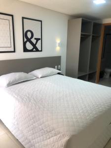 若昂佩索阿Manaíra Apart Hotel的卧室配有一张带两个枕头的大白色床