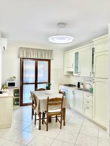 FolignanoLa Casetta的厨房配有白色橱柜和桌椅