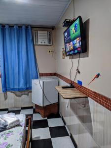 里奥普雷托达伊娃Pousada Aguiar的一间墙上配有电视和一张桌子的房间
