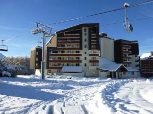 拉普德兹Appartement Huez, 1 pièce, 3 personnes - FR-1-405-87的雪地中的一座建筑,设有滑雪缆车
