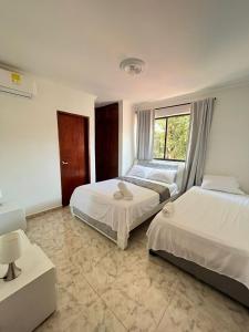 卡塔赫纳Apartamento Vacacional Cartagena Colombia的一间卧室设有两张床和窗户。