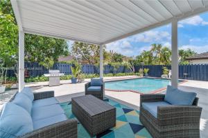 迈阿密Kendall Vacation Luxury Home的一个带椅子的庭院和一个带白色凉棚的游泳池