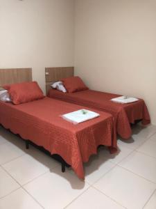 瓜鲁柳斯Attriun Hotel的红色床单的客房内的两张床