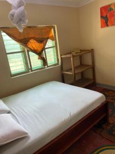 帕杰Afrobukuu house的卧室配有白色的床和窗户。