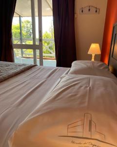 特玛斯德戴曼Hotel Mirador del Dayman的一张带白色床罩的床,配有一盏灯和一扇窗户