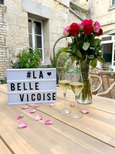 Vic-sur-AisneLa Belle Vicoise的一张桌子,上面放着两杯葡萄酒和一瓶玫瑰花