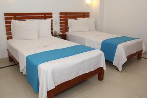 通贝斯HOTEL Casa cesar的客房内的两张床,配有白色和蓝色的床单