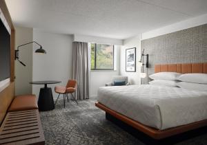 大急流城Sheraton Grand Rapids Airport Hotel的酒店客房配有一张床铺和一张桌子。