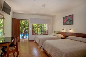 利比里亚博伊罗斯酒店的一间卧室设有三张床、一张书桌和窗户。