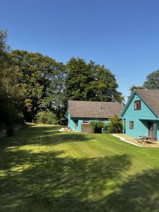 德里门Foxglove Cottages的草坪上的蓝色房子,有树在后面