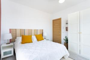 格拉纳迪利亚德亚沃纳EDEN RENTALS 102 Surfy Stylish Bed&Coffee Balcony的白色卧室配有一张白色大床和黄色枕头